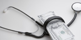 Stethoscope wrapped around hundred dollar bills