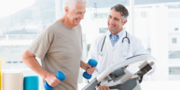 Senior man on treadmill with therapist in fitness studio where patients are treated.