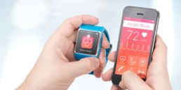 A cell phone and a smartwatch side-by-side, neither are clinical wearables.