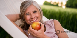 Middle aged woman eating whole, fresh apple.