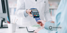 Patient paying for medications and/or services at a doctors office, big data plays a role via computer screen and payment device.