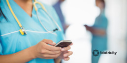 A nurse is text messaging on a mobile phone.